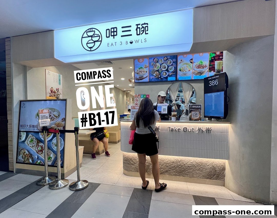 The entrance of Eat 3 Bowls restaurant at Compass One, showing the counter and menu displays.