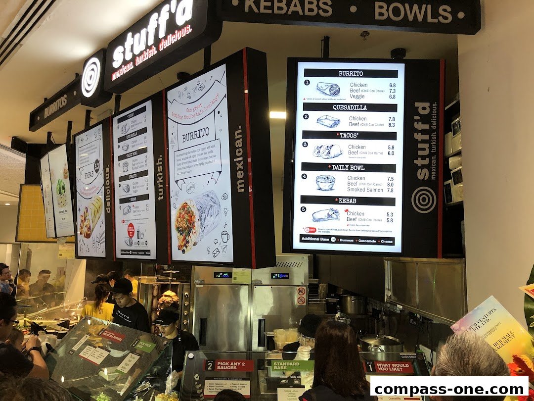 A busy food counter at Stuff'd, showcasing digital menus with various Mexican and Turkish dishes.