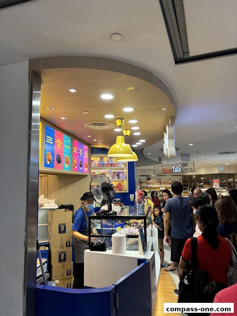 A Famous Amos cookie shop with a queue of customers and a staff member serving.