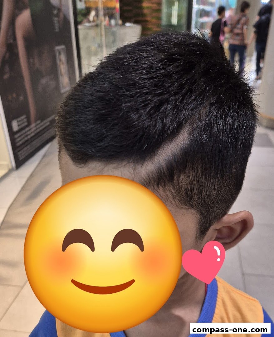 A close-up of a child's haircut with a smiley face emoji covering their face.