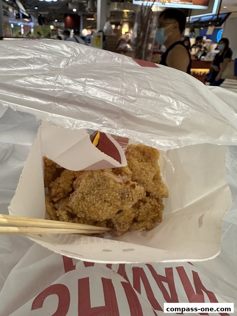 A bag of crispy fried chicken pieces from Shihlin Taiwan Street Snacks with chopsticks.