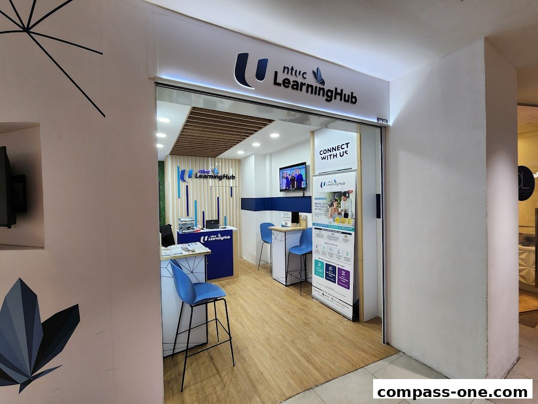 The entrance to NTUC LearningHub at Compass One, featuring a modern interior and promotional materials.