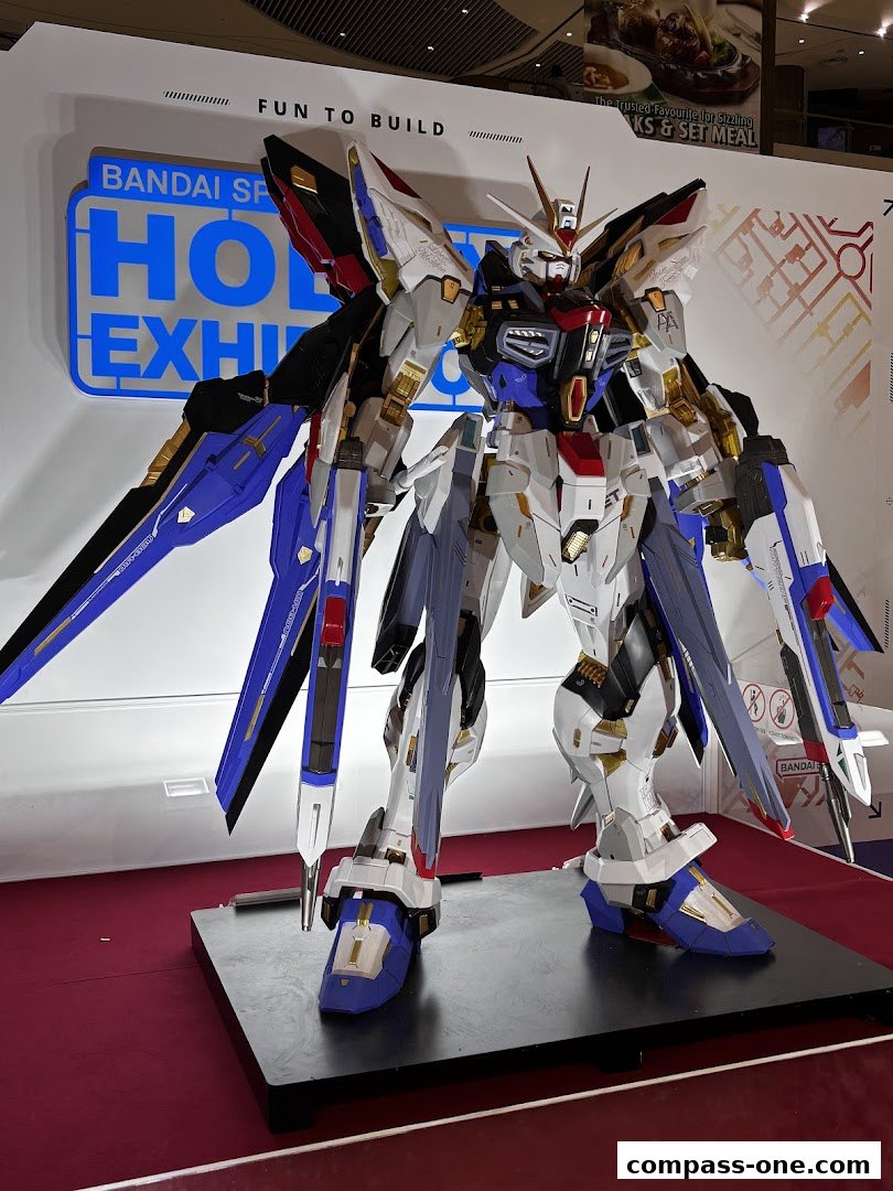 A large, detailed Gundam model is displayed at a hobby exhibition.
