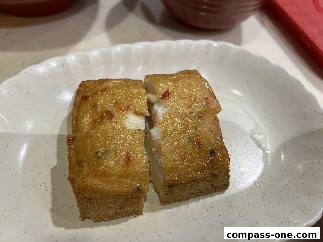 Two golden-brown fried fish cakes are served on a white plate with a scalloped edge.