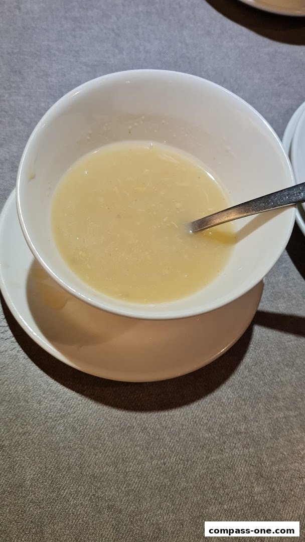 A bowl of creamy soup with a spoon resting inside, served on a saucer.