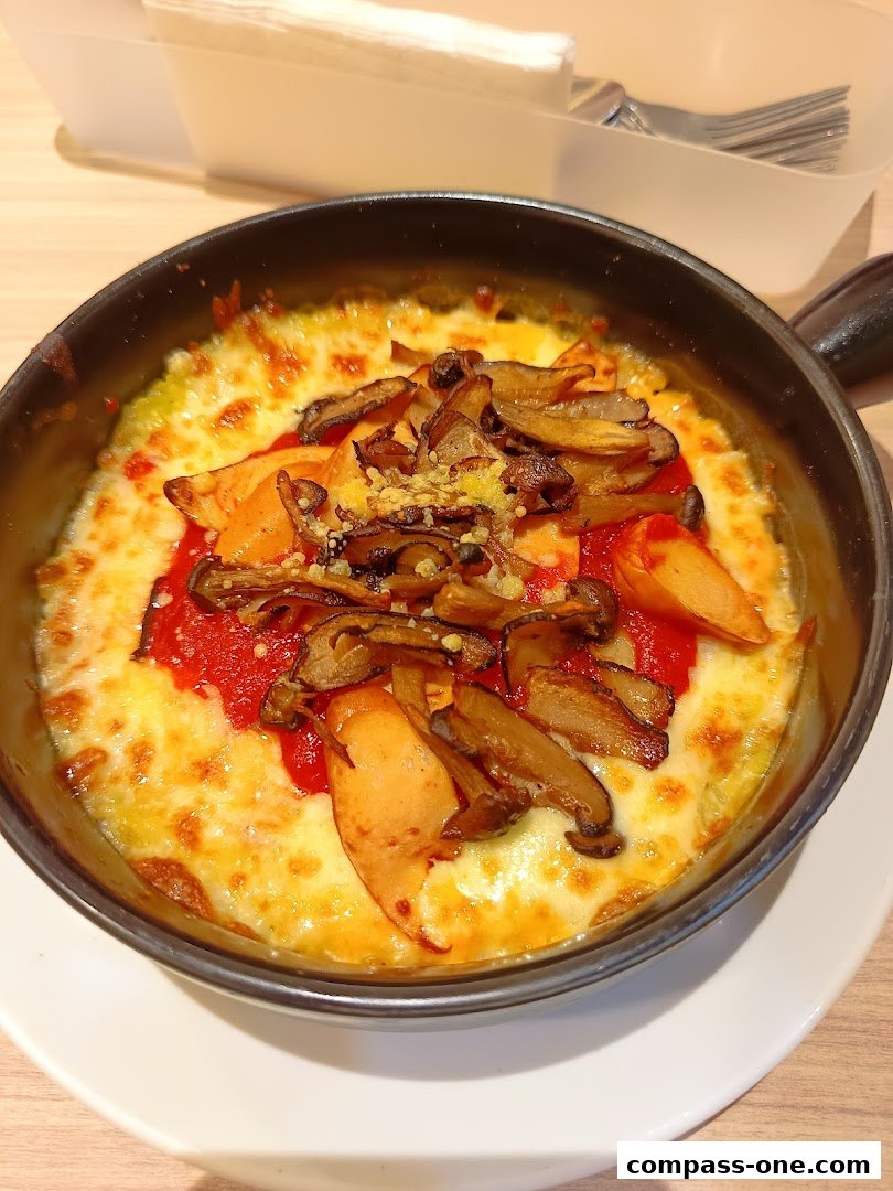 A close-up of a baked dish with melted cheese, mushrooms, and tomato sauce.