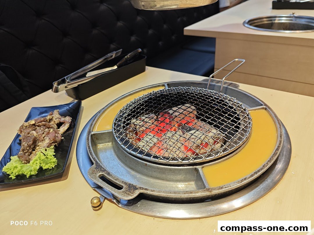 A plate of marinated meat and a grill with glowing coals at a Korean dining restaurant.