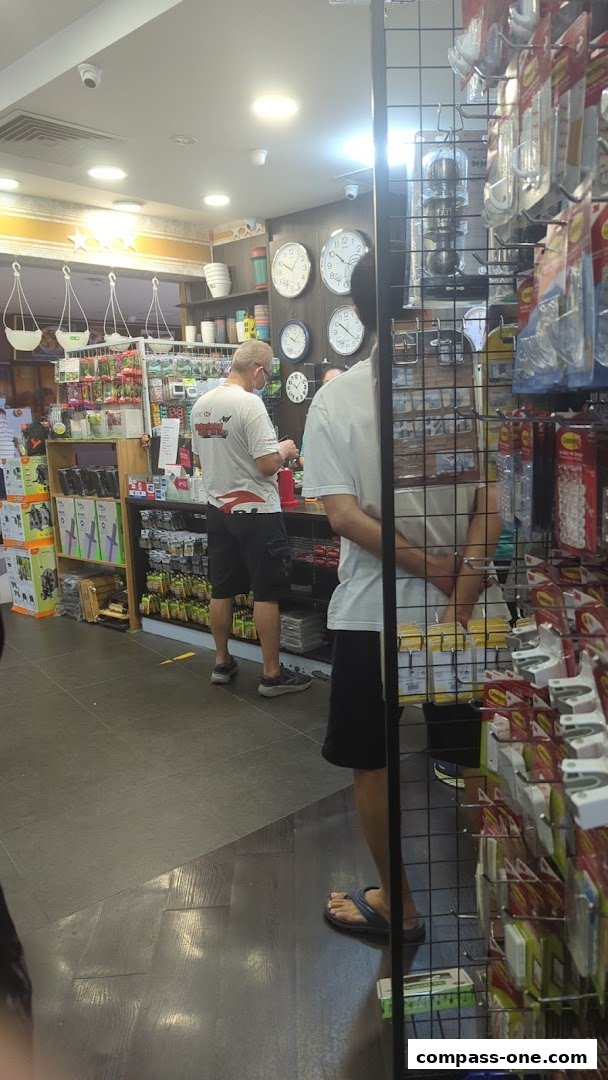 Interior of a household goods store with customers browsing shelves stocked with various items.