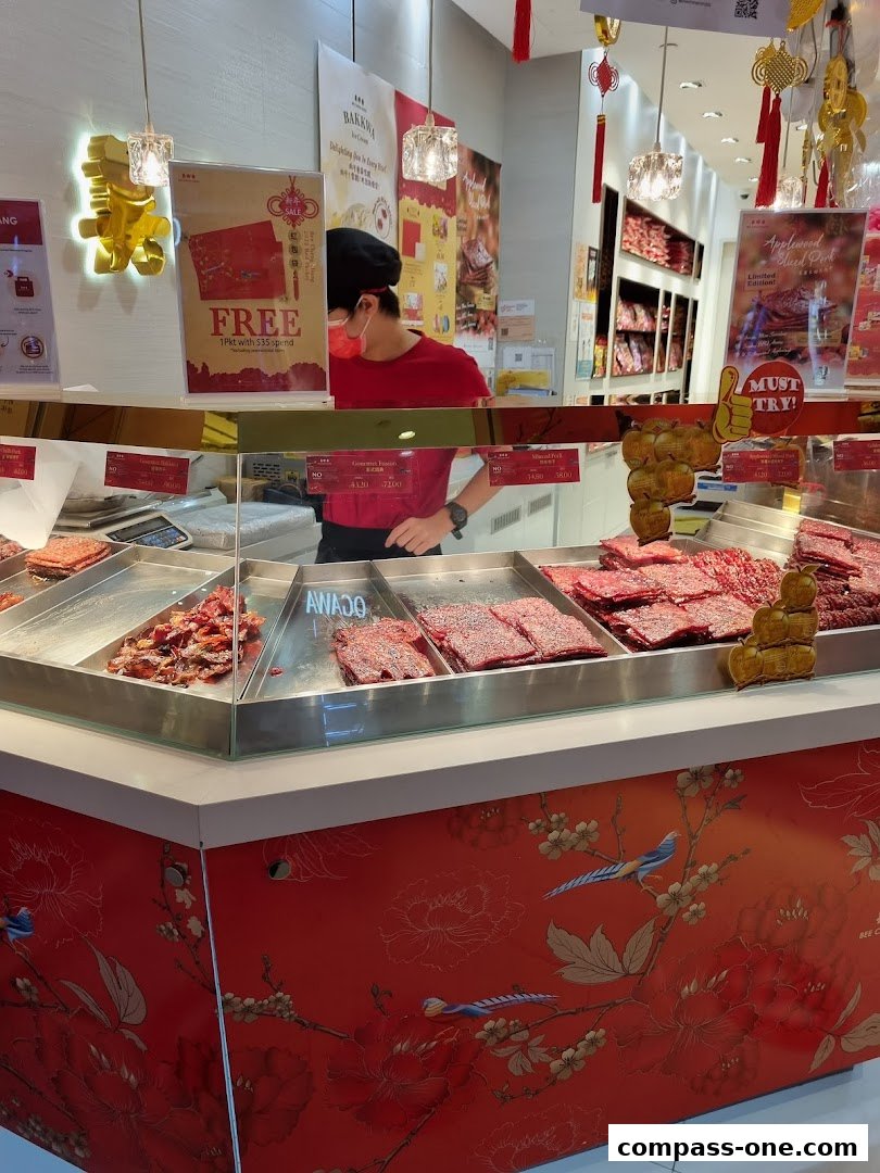 A shop interior displaying various types of bak kwa with a staff member behind the counter.