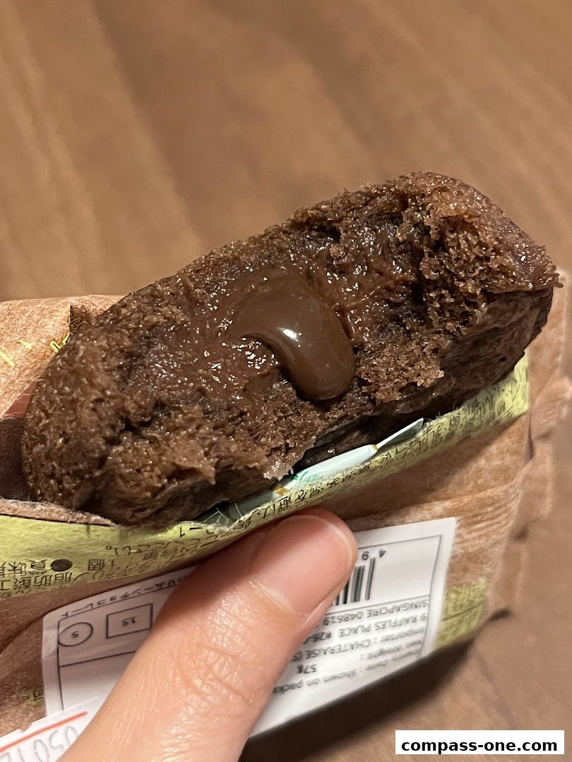 A hand holds a chocolate cake with a gooey chocolate filling.