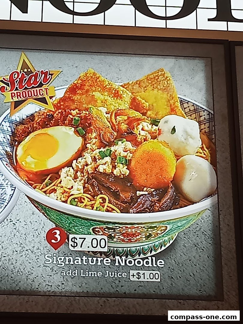 A close-up of a signature noodle dish with a fried egg, meat, and wontons.