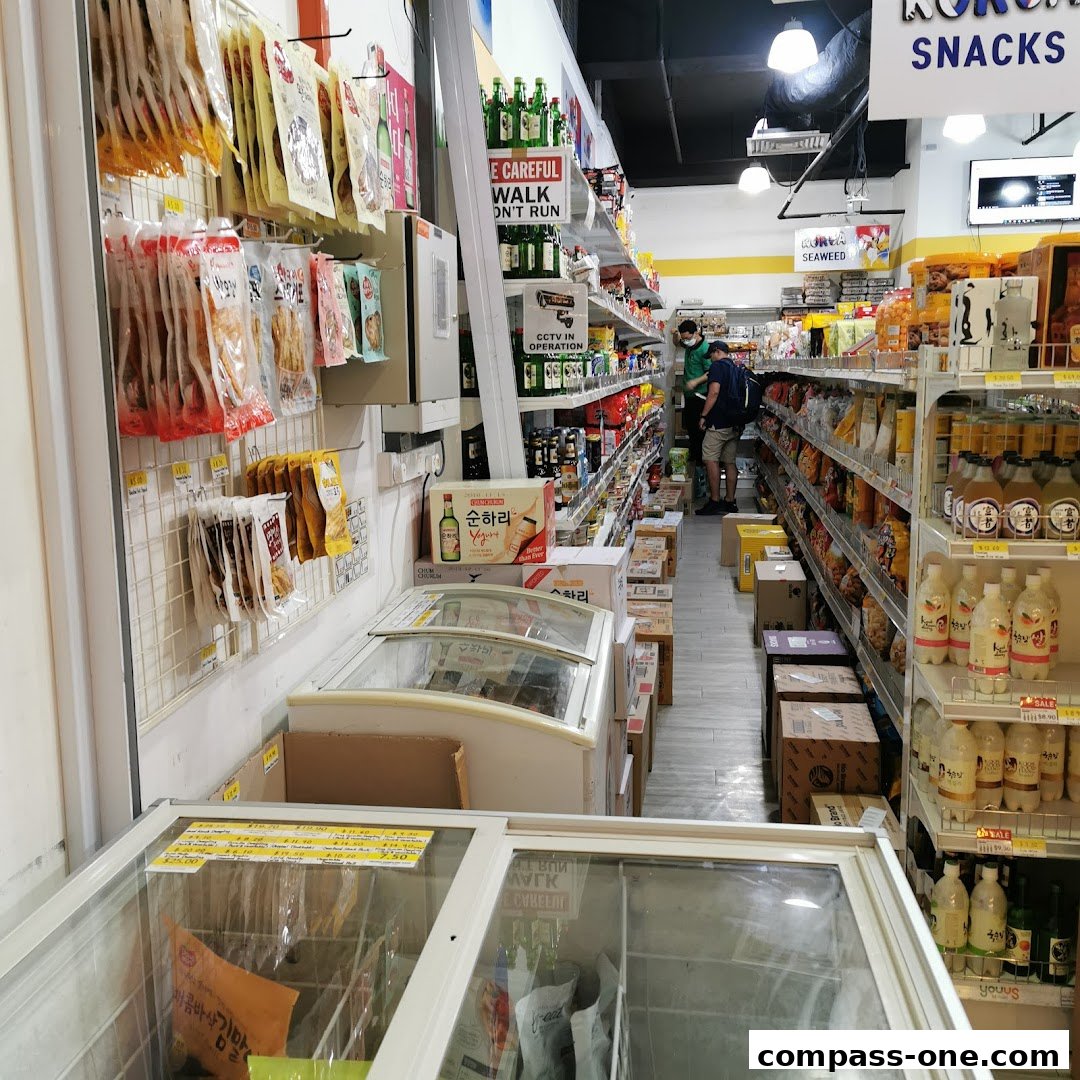Interior view of a Korean mart with shelves stocked with snacks, drinks, and frozen goods.