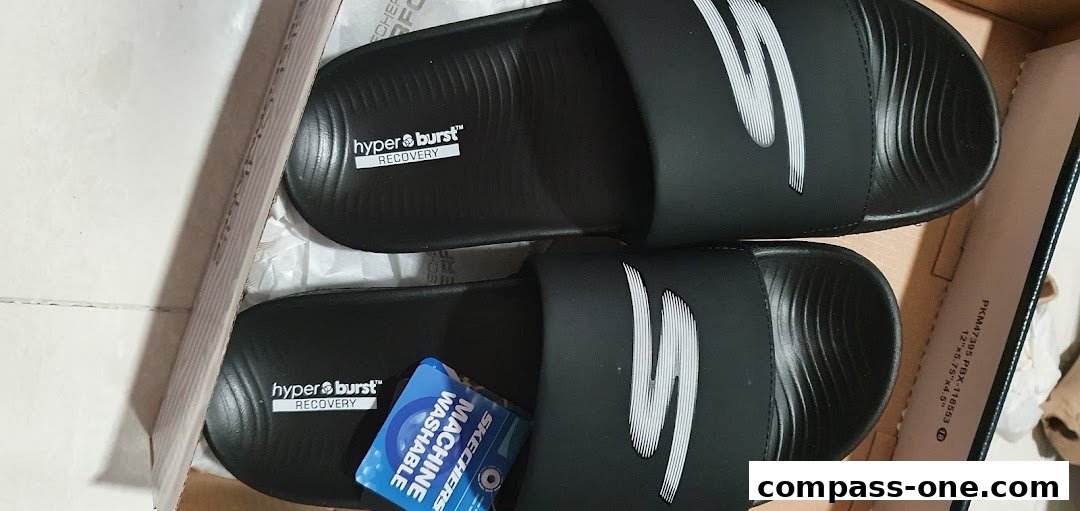 A pair of black Skechers slides with the 'S' logo and 'hyper burst recovery' branding inside a box.