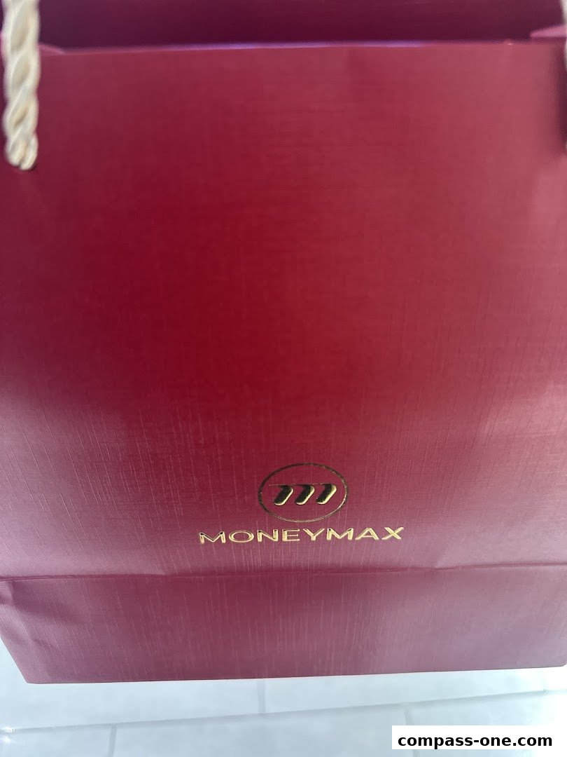 A close-up of a red shopping bag with the MoneyMax logo and gold lettering.