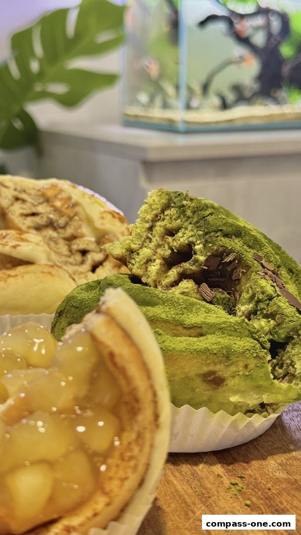 Close-up of delicious pastries, including a matcha-dusted roll and a fruit tart.