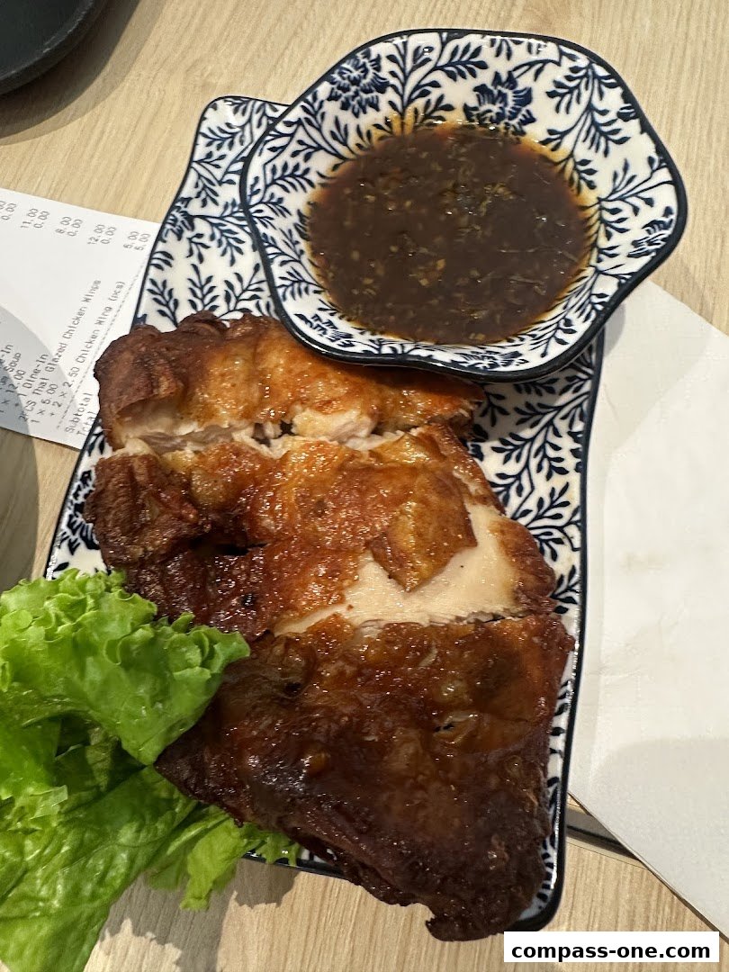 A plate of delicious Thai glazed chicken wings with a side of dipping sauce and lettuce.