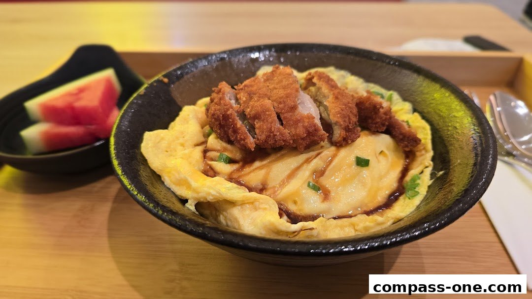 A close-up of a delicious ramen dish with crispy chicken and a side of watermelon.