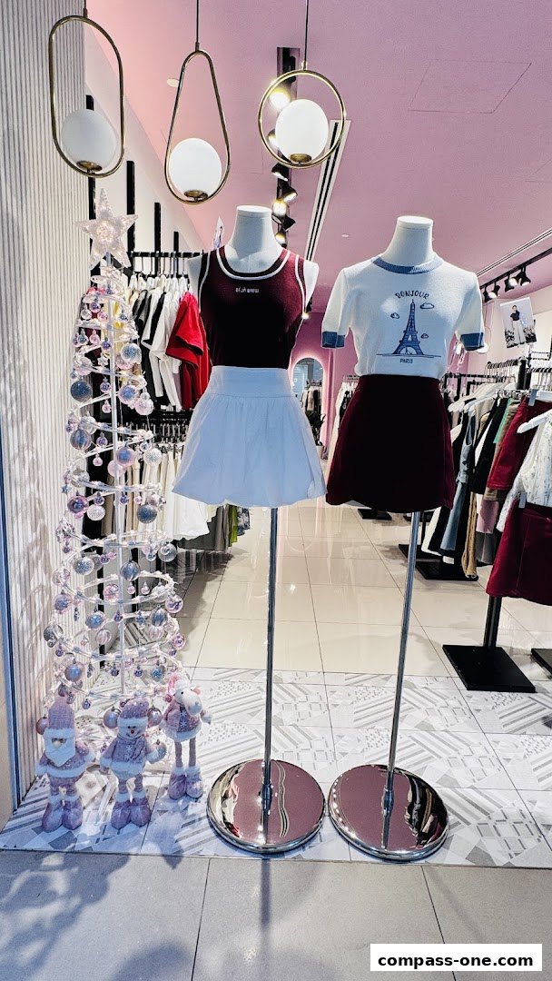 Mannequins display fashionable outfits in a brightly lit store with festive decorations.