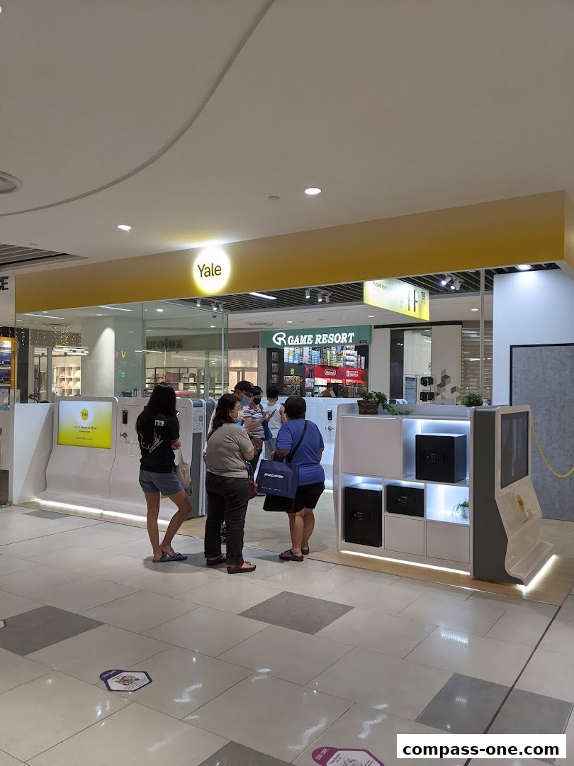 People are standing at a Yale Smart Shop display featuring safes and interactive screens.