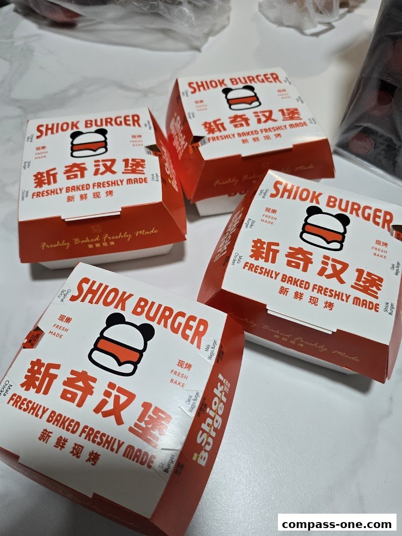 Four red and white Shiok Burger boxes are arranged on a white surface.