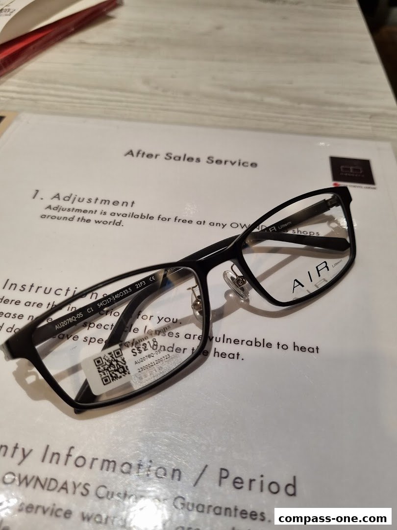 A pair of black OWNDAYS glasses with a price tag and service information.