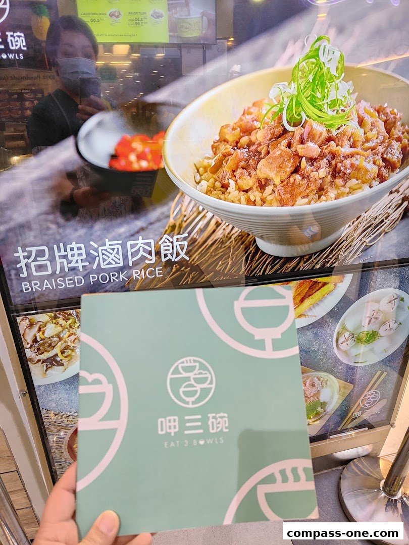 A person holds a menu in front of a display featuring braised pork rice.