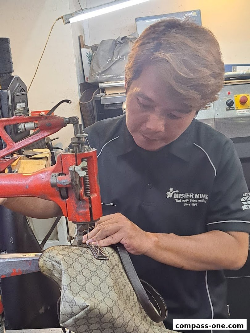 A Mister Minit employee repairs a designer handbag using a sewing machine.