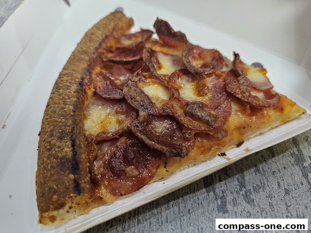 A close-up shot of a delicious slice of pepperoni pizza in a white box.