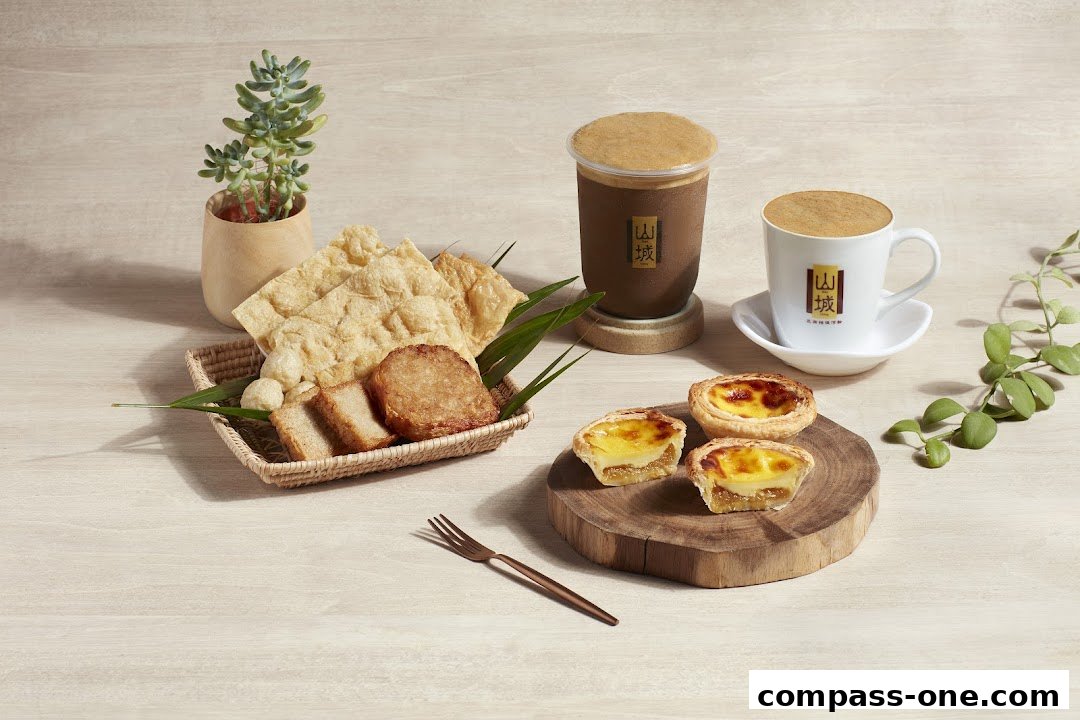 A spread of Ipoh delicacies including egg tarts, fried snacks, and beverages.