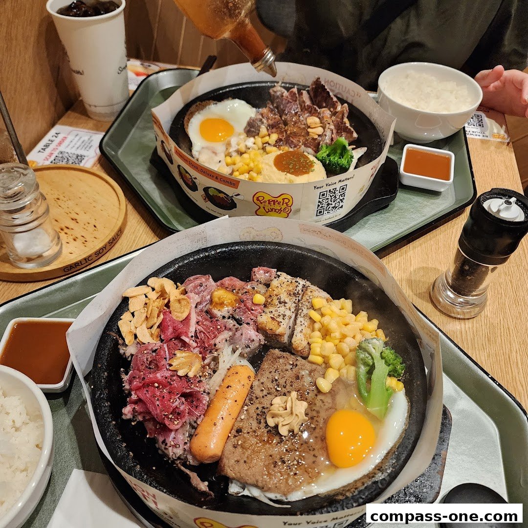 Two sizzling hot plates of food, featuring steak, chicken, sausage, egg, corn, and broccoli.