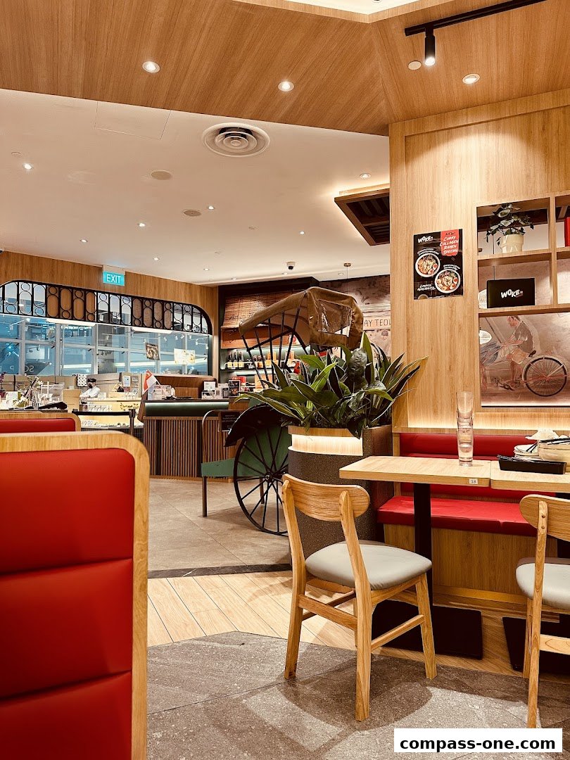 Interior view of WOKE Ramen restaurant with wooden decor, red seating, and a traditional rickshaw.