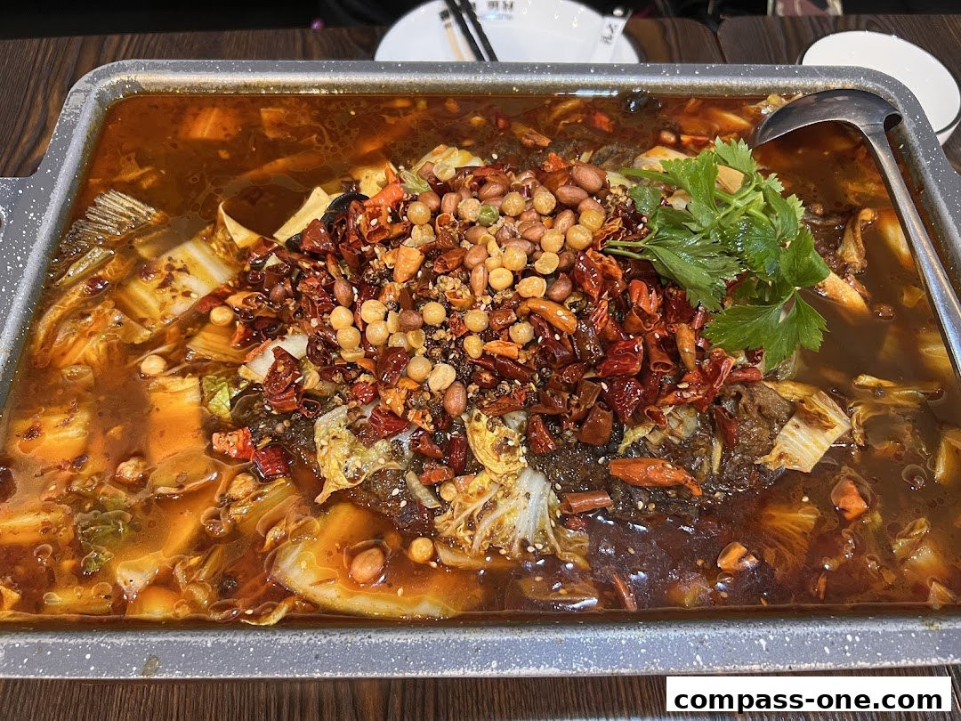 A close-up of a sizzling grilled fish dish with chili peppers, peanuts, and vegetables.