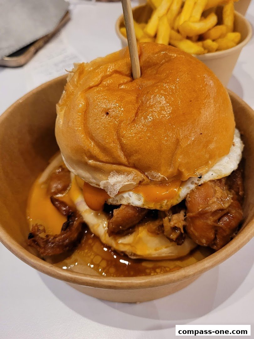 A close-up of a juicy burger with a fried egg and fries in the background.
