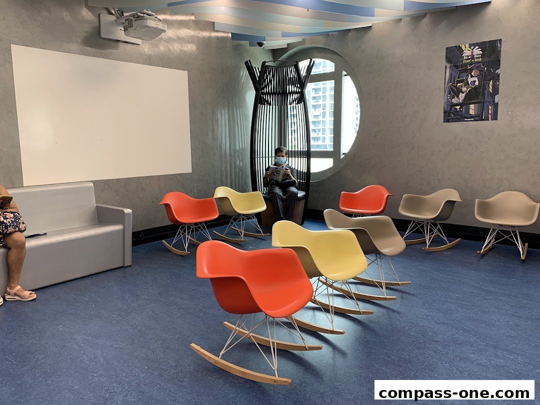A waiting area with colorful rocking chairs and a person reading a book.