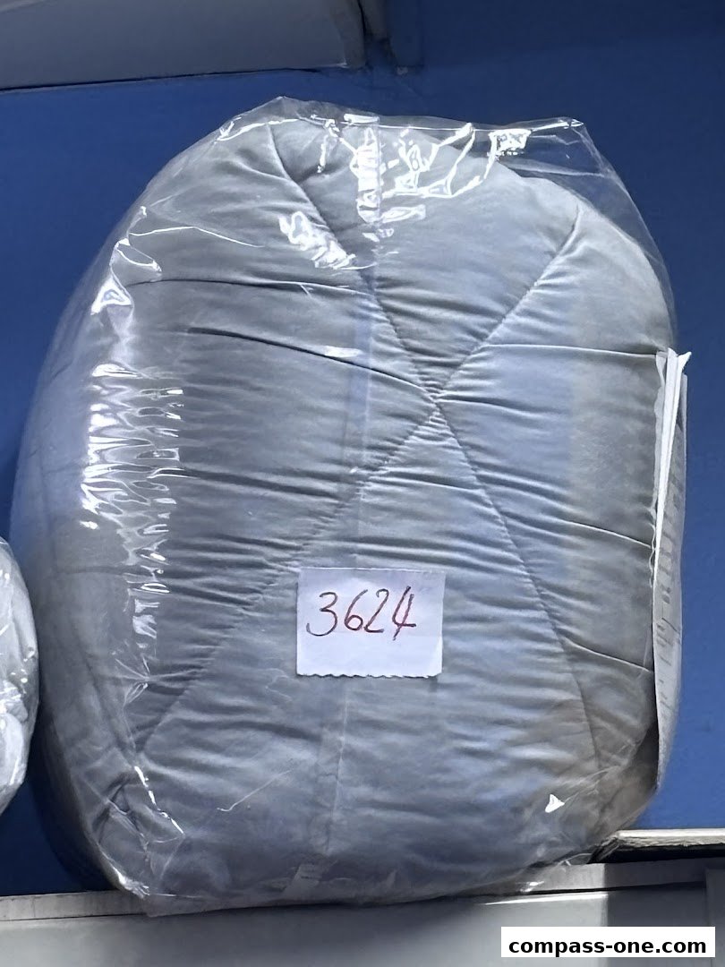 A gray comforter or duvet, sealed in plastic, with a handwritten tag displaying '3624'.