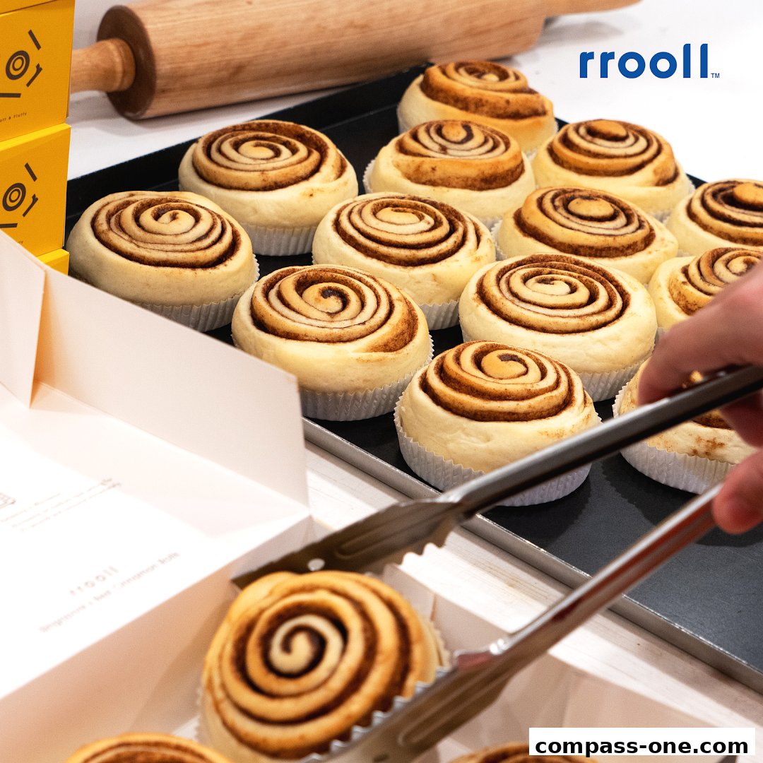 A tray of freshly baked cinnamon rolls being served with tongs.