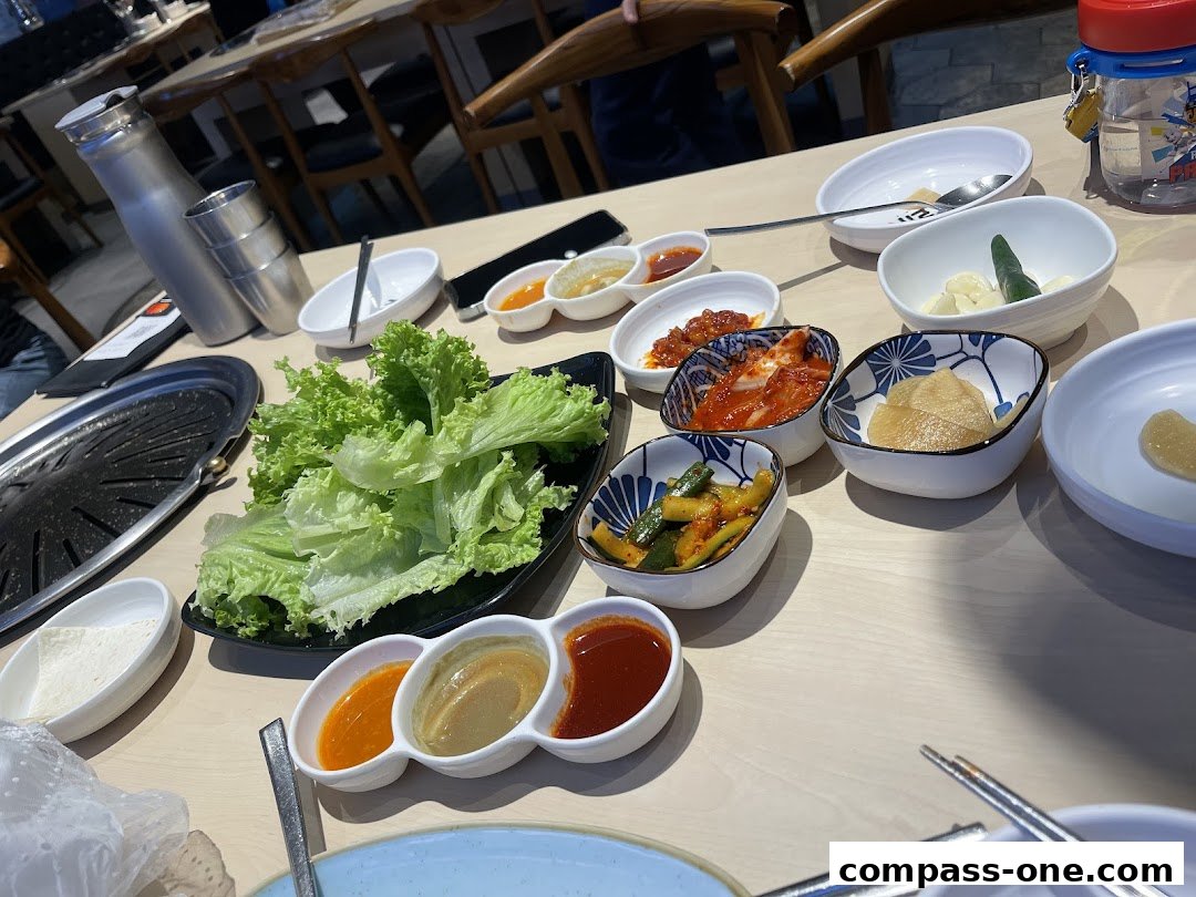 A table set with Korean BBQ ingredients including lettuce, kimchi, and various dipping sauces.