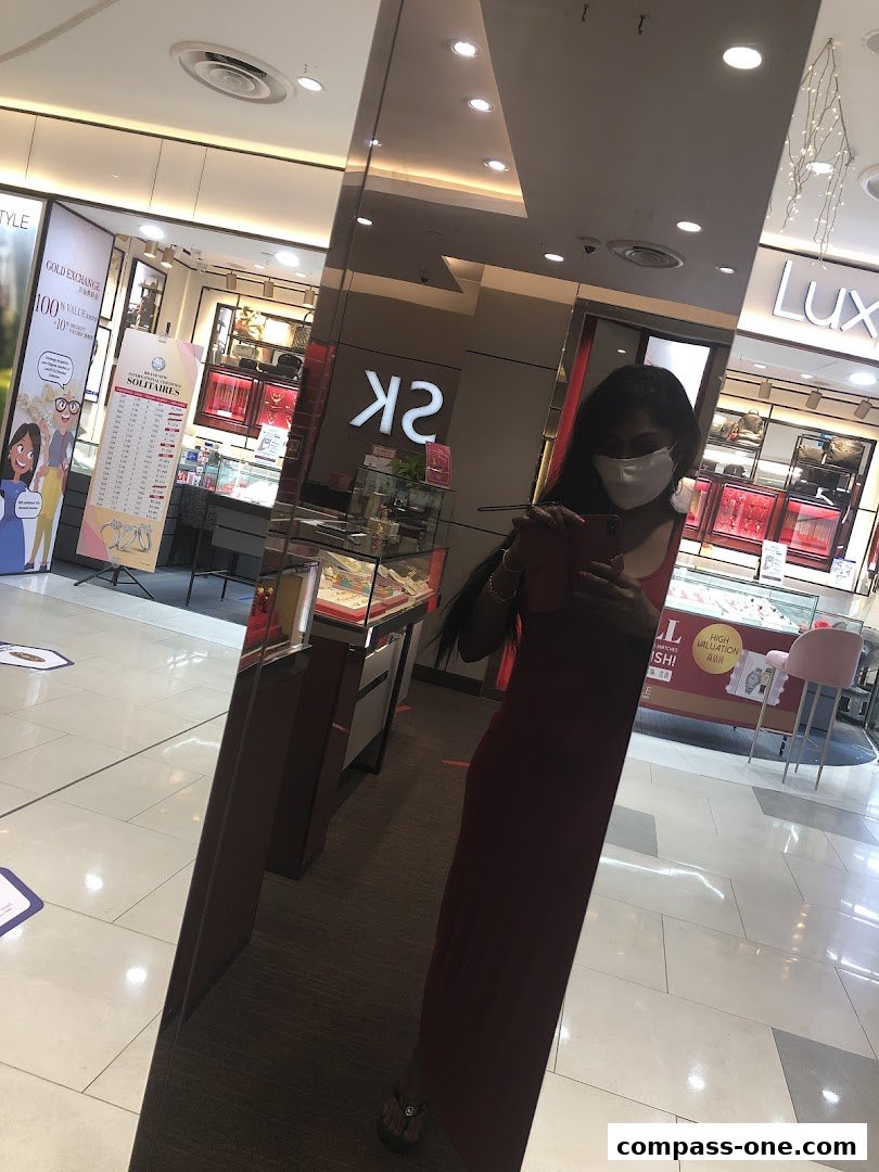 A person in a mask reflects in a mirror in front of a jewelry store.