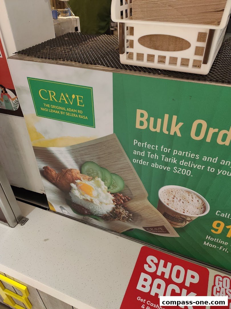 A counter display for Crave Nasi Lemak, featuring a Nasi Lemak dish and a cup of Teh Tarik.
