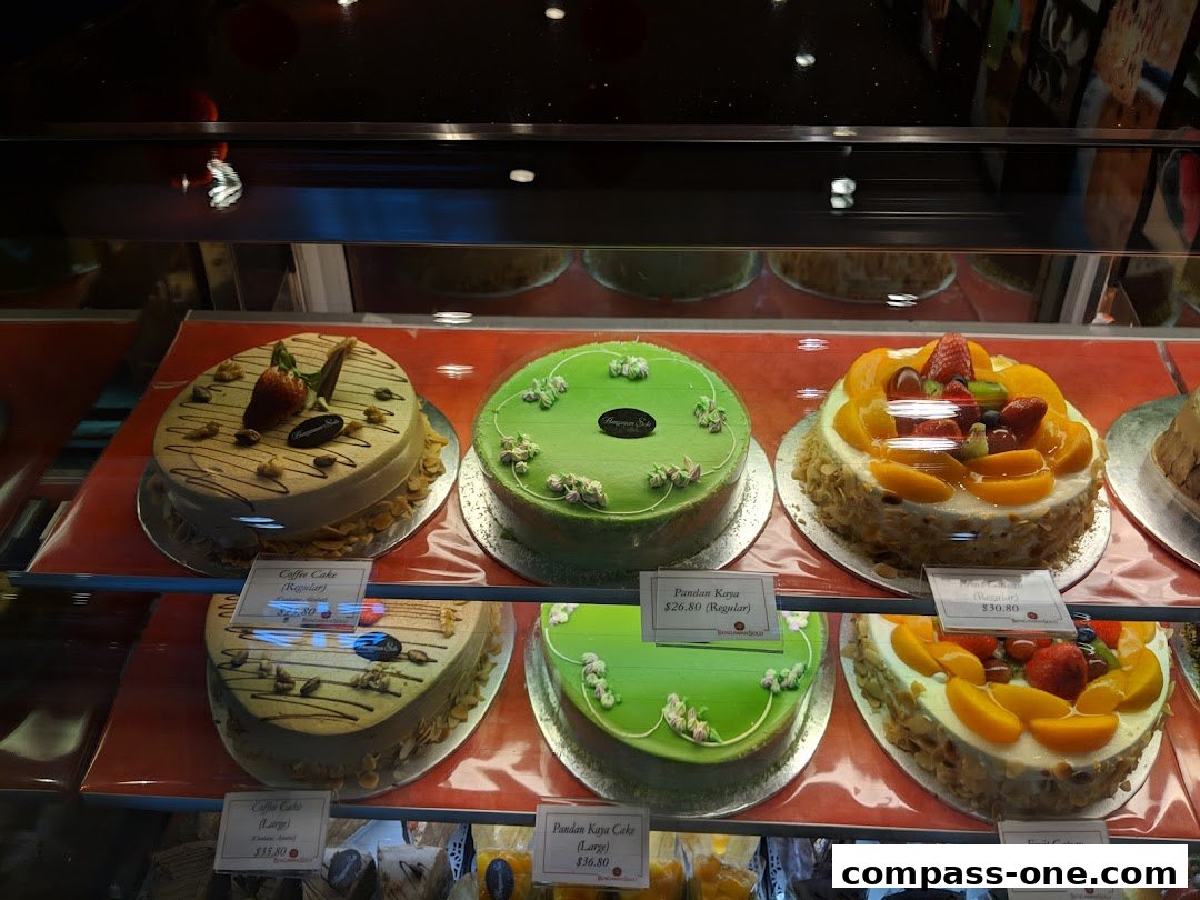 A display of beautifully decorated cakes, including coffee, pandan kaya, and fruit flavors.
