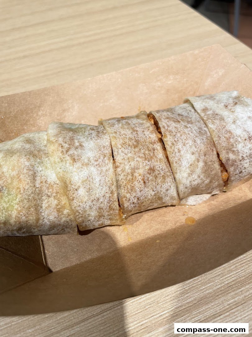 A close-up shot of a sliced popiah roll served in a brown paper tray.