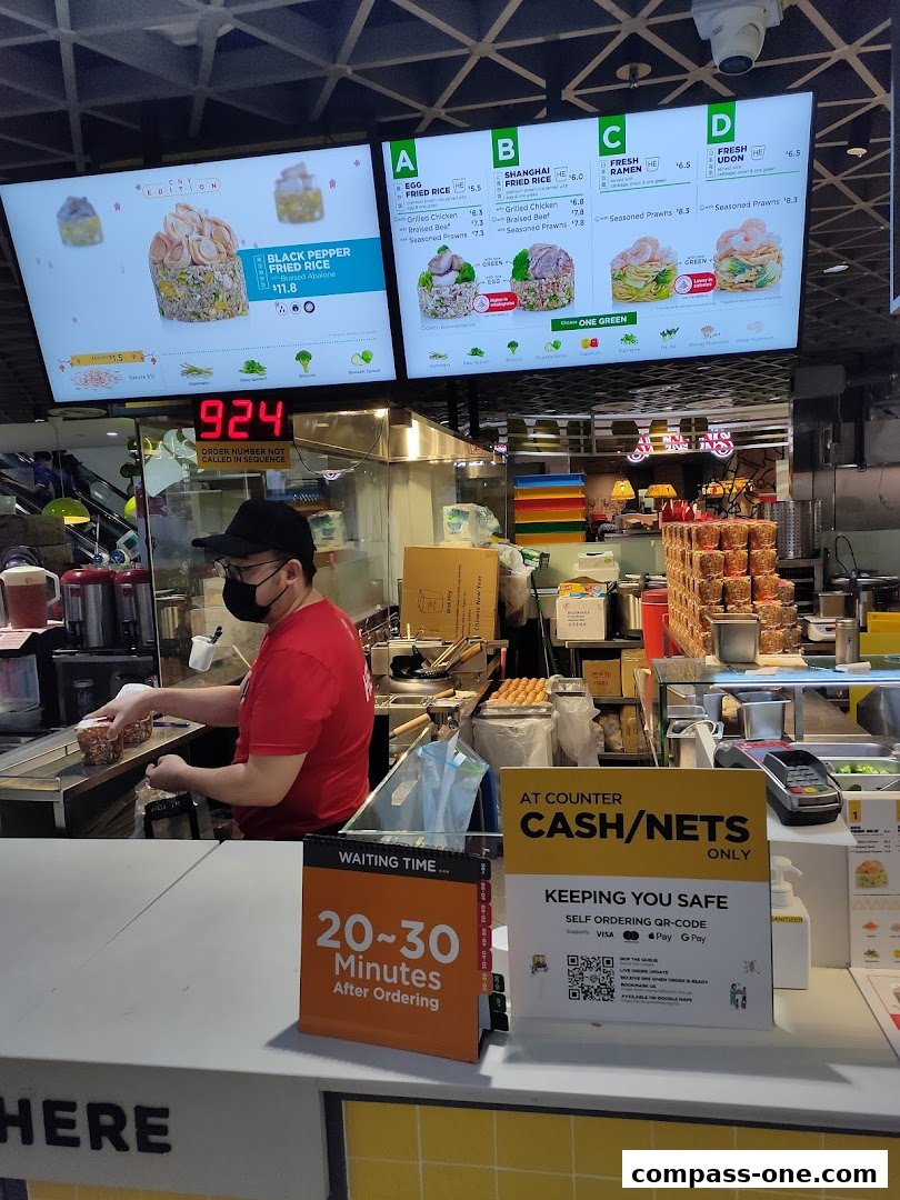 A Wok Hey counter with a digital menu displaying food options and a staff member preparing an order.