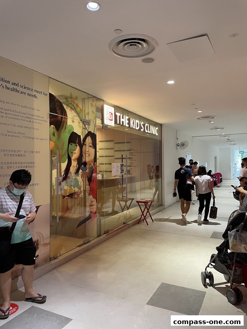The exterior of 'The Kid's Clinic' with a glass facade and signage, showing people walking by.