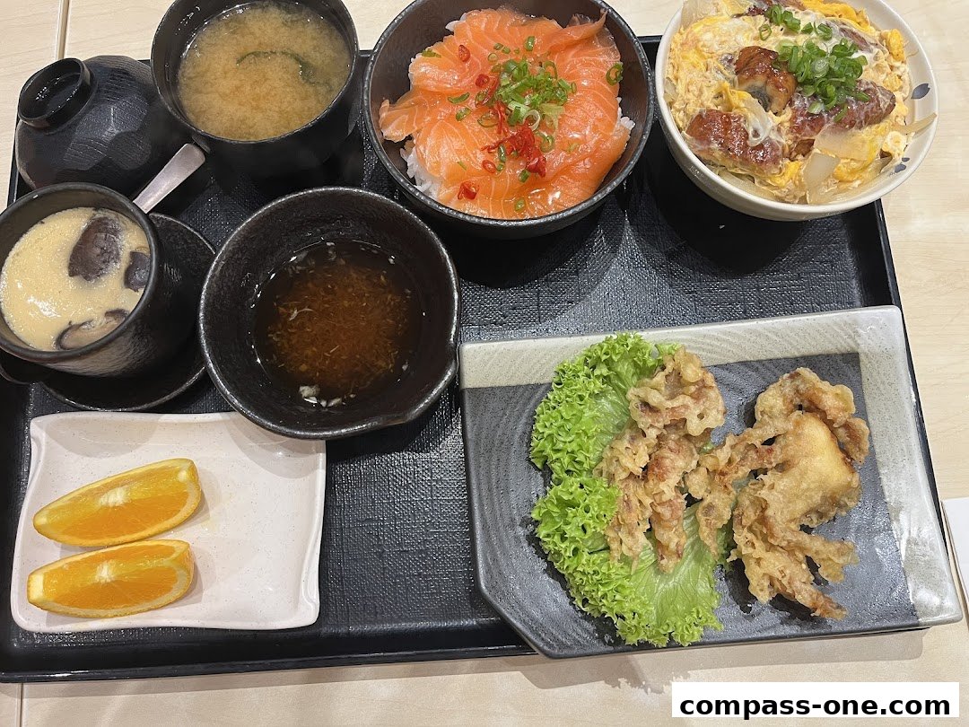 A Japanese meal set featuring salmon sashimi rice bowl, eel rice bowl, fried chicken, and miso soup.