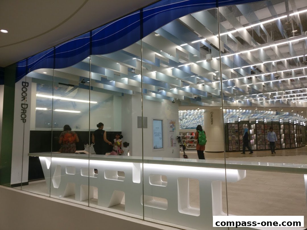 Interior view of a modern library with a book drop and children's section.