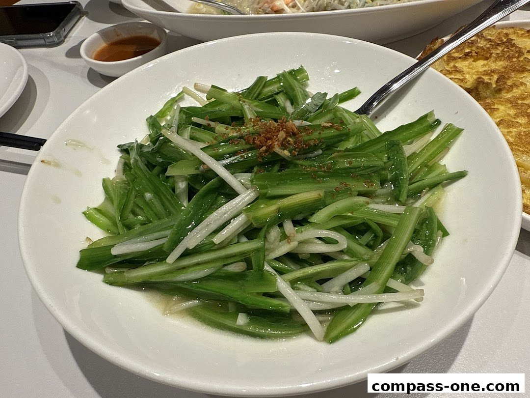 A close-up of a white plate filled with stir-fried green vegetables and a side of omelet.