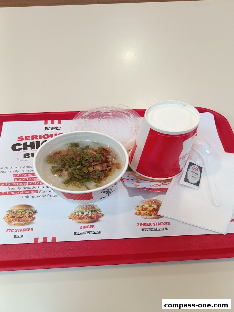 A KFC meal featuring a bowl of congee, a drink, and a napkin on a red tray.