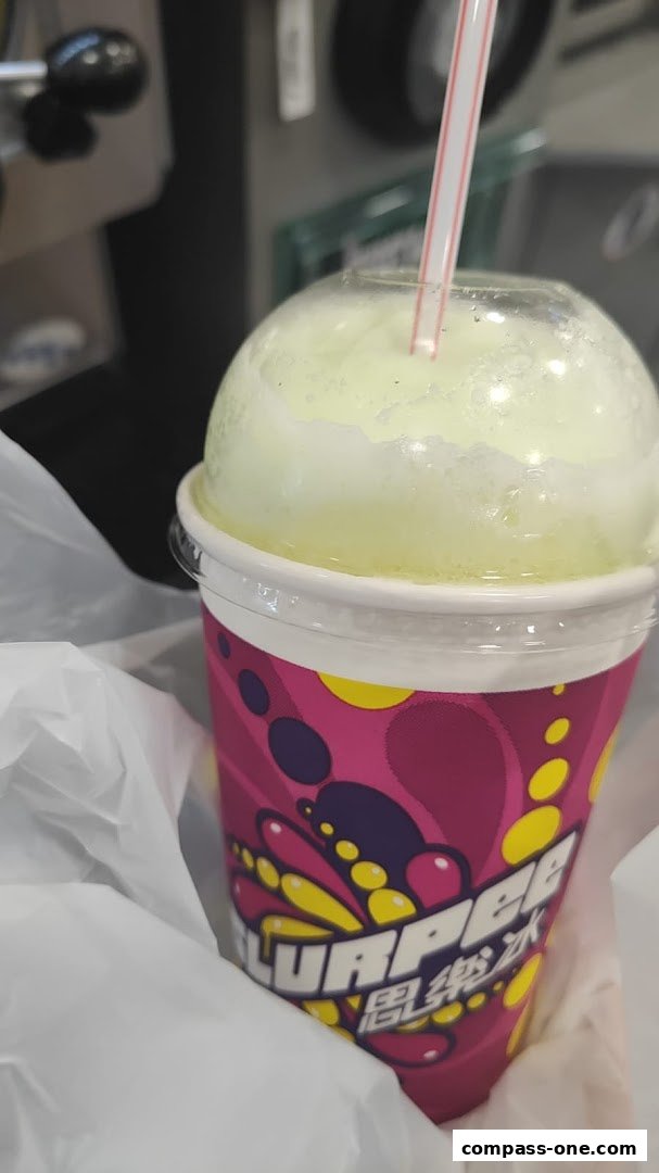 A close-up of a colorful Slurpee cup with a straw and a white plastic bag.