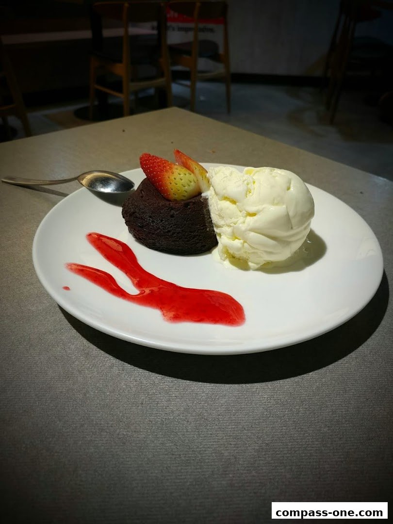 A chocolate lava cake with vanilla ice cream and strawberries on a white plate.