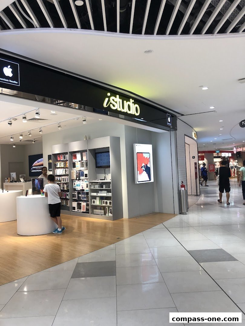 The iStudio store entrance with Apple products displayed inside and a young customer interacting with a display.
